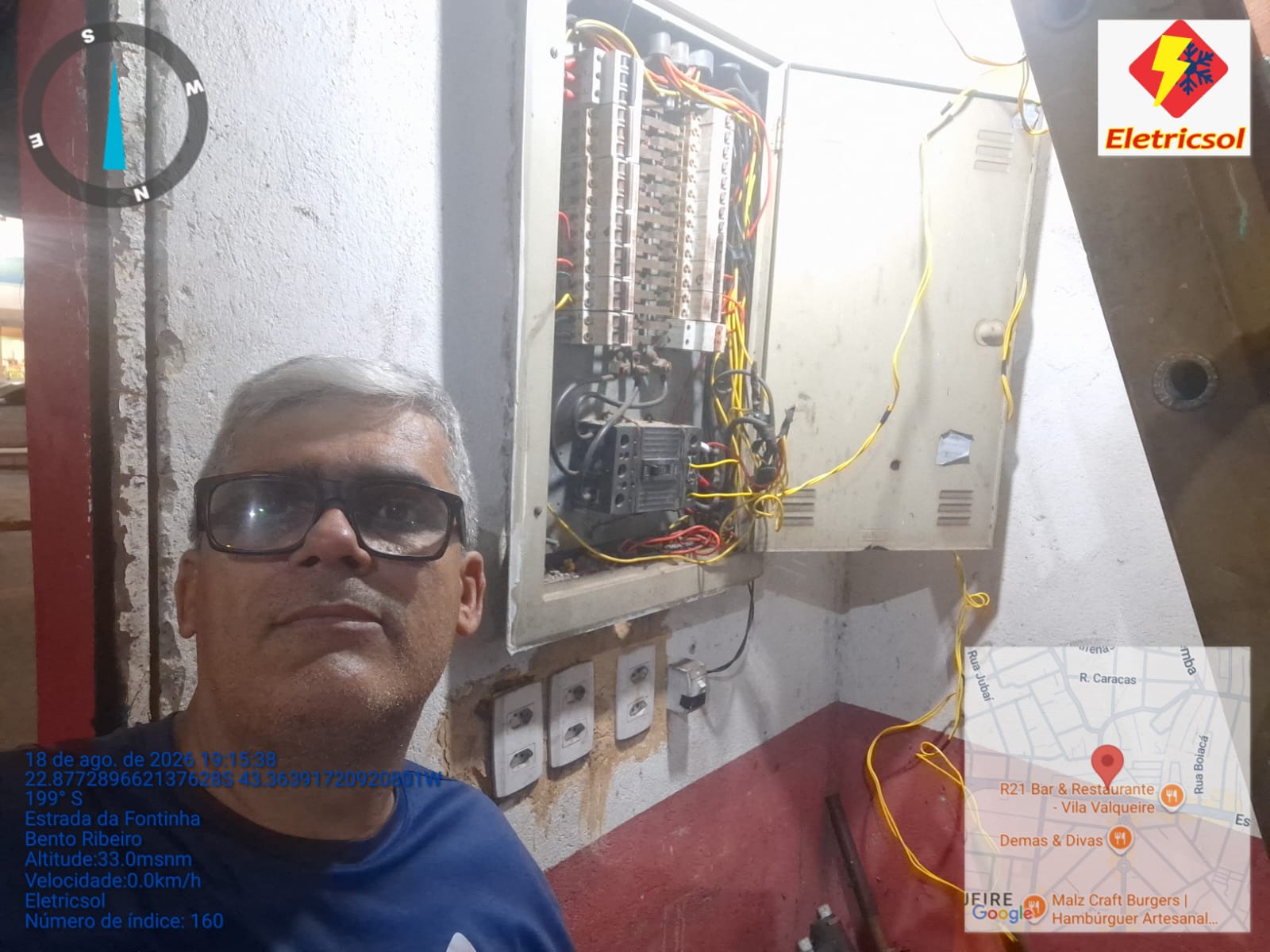 Eletricista em frente a quadro de distribuição aberto com fiação em manutenção